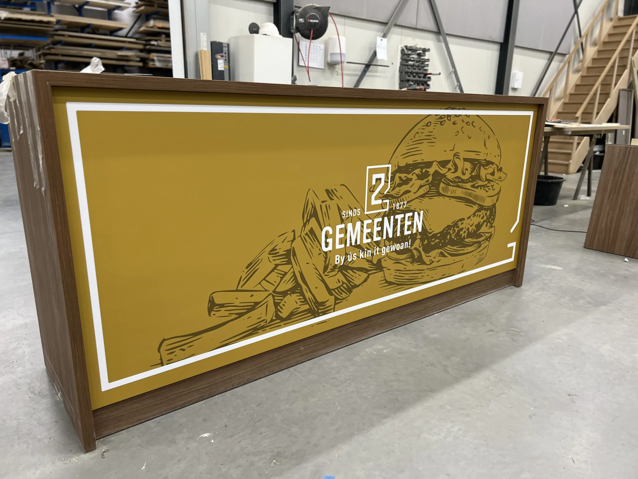 Een houten balie van de Twee gemeenten in Jirnsum die door Pieter Plakt is voorzien vaan een fullcolour opdruk met hun logo